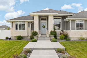 Prairie-style home with a front lawn, a shingled roof, and stone siding