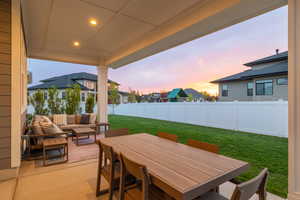 Patio terrace at dusk featuring outdoor living area, outdoor dining area, and a fenced yard