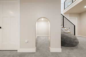 Under-stairs play space with carpeted flooring and two-tone paint