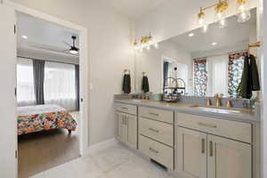 Ensuite bathroom with double vanity, quartz countertops, gold fixtures, and tile flooring