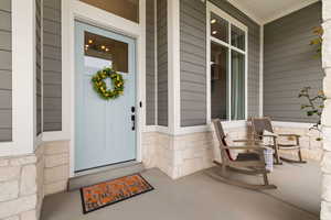 View of exterior entry featuring a porch and stone siding