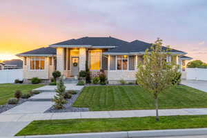 Prairie-style house with a professionally landscaped front yard, covered porch, exterior lighting, mixed finishes of cement-fiber siding and light colored stone