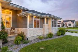 Prairie-style house with a professionally landscaped front yard, covered porch, exterior lighting, mixed finishes of cement-fiber siding and light colored stone