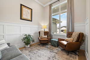 Font living area featuring light hardwood floors, a wainscoted wall, crown molding, and two-tone paint