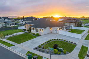 View of front of property with a garage, a residential view, a lawn, driveway, and stone siding