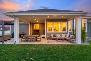 Back of house featuring a covered patio area with outdoor living space, exterior lighting and a hot tub with pergola