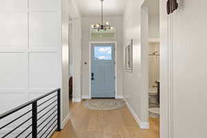Entryway with light hardwood floors, modern chandelier, and two-tone paint