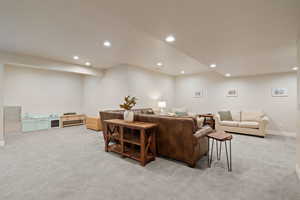 Carpeted open floorplan living space with two-tone paint and recessed lighting