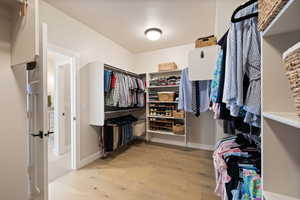 Spacious walk-in closet with light hardwood floors