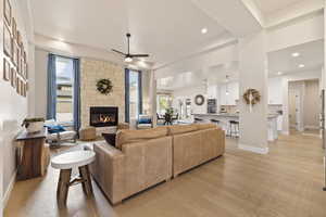 Living area featuring ceiling fan, recessed lighting, a stone fireplace, light hardwood floors, and plenty of natural light