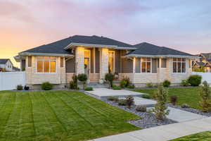Prairie-style house with a professionally landscaped front yard, covered porch, exterior lighting, mixed finishes of cement-fiber siding and light colored stone