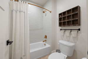 Basement bathroom with tiled shower / tub combo, toilet, and two-tone paint