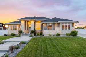 Prairie-style house with a professionally landscaped front yard, covered porch, exterior lighting, mixed finishes of cement-fiber siding and light colored stone