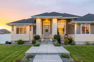 Prairie-style house with a professionally landscaped front yard, covered porch, exterior lighting, mixed finishes of cement-fiber siding and light colored stone