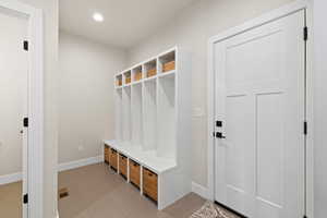 Mudroom with recessed lighting, light tile flooring, and locker-style mud bench with storage shelves