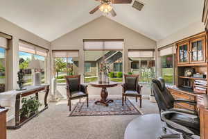 Carpeted office with a ceiling fan, baseboards, visible vents, and vaulted ceiling