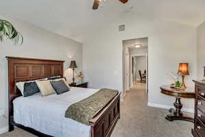 Bedroom with visible vents, baseboards, high vaulted ceiling, and light colored carpet