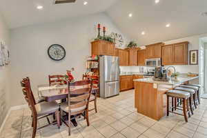 Kitchen featuring appliances with stainless steel finishes, light tile patterned flooring, a peninsula, and high vaulted ceiling