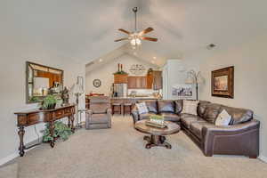 Living area with ceiling fan, light carpet, baseboards, and lofted ceiling