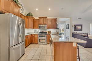 Kitchen with a sink, a peninsula, open floor plan, stainless steel appliances, and light tile patterned flooring