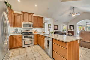 Kitchen featuring appliances with stainless steel finishes, a sink, light tile patterned floors, a peninsula, and open floor plan