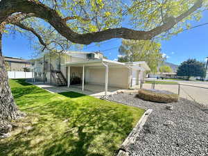 View of home's exterior featuring fence, brick siding, a patio area, a lawn, and stairway