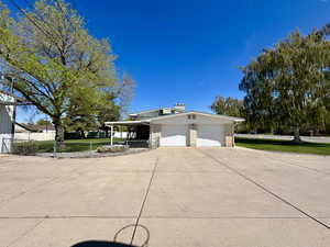 Expansive driveway with a garage, brick siding, and fence