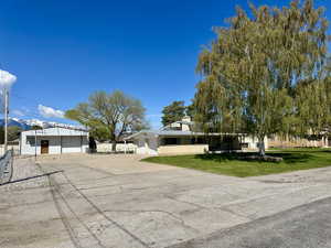 View of front of property with view of large useful shop and very functional driveway, and a front yard