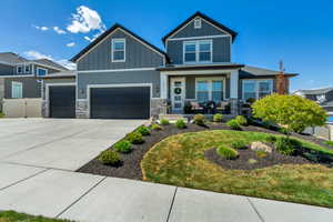 Craftsman house featuring a garage, covered porch, stone siding, board and batten siding, and driveway