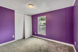 Carpeted spare room featuring baseboards and a textured ceiling