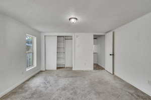 Unfurnished bedroom with carpet floors, baseboards, a closet, and a textured ceiling
