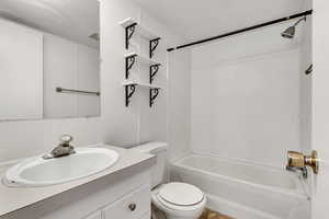 Full bath featuring visible vents, vanity, toilet, a textured ceiling, and shower / washtub combination