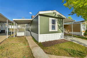 View of front of property with covered porch, a front lawn, and a carport