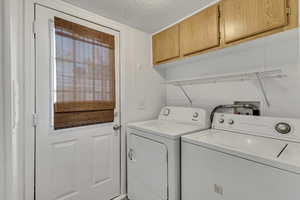 Laundry room featuring a textured ceiling, cabinet space, and washer and dryer