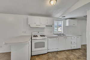 Kitchen with a peninsula, white appliances, light countertops, under cabinet range hood, and a sink