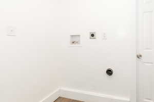 Clothes washing area featuring hookup for an electric dryer, wood finished floors, washer hookup, and laundry area