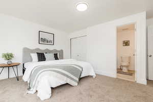 Bedroom featuring baseboards, ensuite bathroom, a closet, and carpet