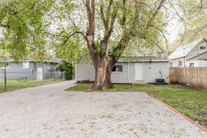 Rear view of property with fence, cooling unit, and driveway