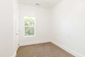 Empty room featuring baseboards, visible vents, and light carpet