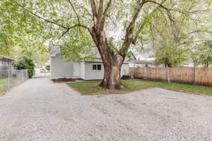Back of property featuring central air condition unit, roof with shingles, and fence