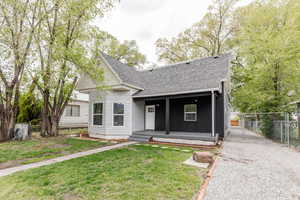 View of front of house featuring a front yard, fence, a shingled roof, and a gate