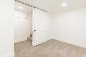 Finished below grade area with baseboards, light carpet, recessed lighting, and stairs