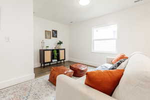 Living room featuring visible vents, wood finished floors, and baseboards