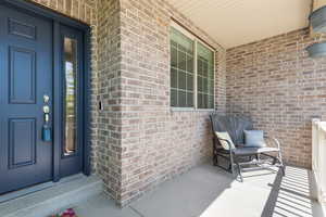 Property entrance featuring covered porch and brick siding
