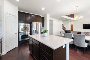 Kitchen with open floor plan, appliances with stainless steel finishes, dark wood-style floors, and dark brown cabinets