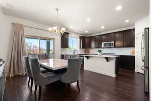Dining space featuring recessed lighting, an inviting chandelier, and dark wood-type flooring