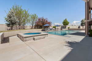 View of swimming pool with a fenced backyard, a fenced in pool, an in ground hot tub, and a patio area