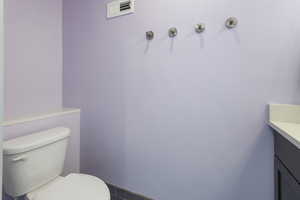 Bathroom featuring vanity, visible vents, and toilet