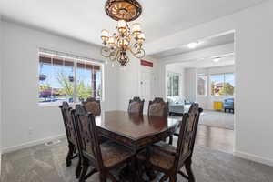 Dining space featuring carpet flooring, a chandelier, baseboards, and visible vents