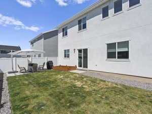 Rear view of house featuring a yard, a patio, fence, and stucco siding